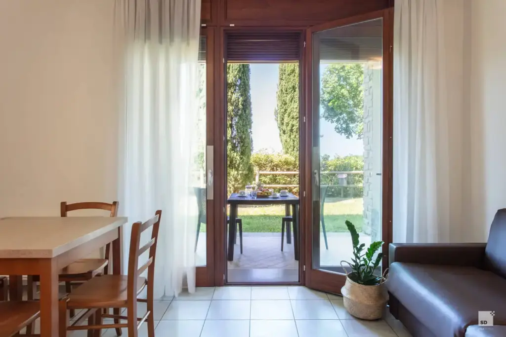 Vista dall'interno dell'appartamento verso il patio esterno e il giardino alberato del Chianti Village Morrocco.